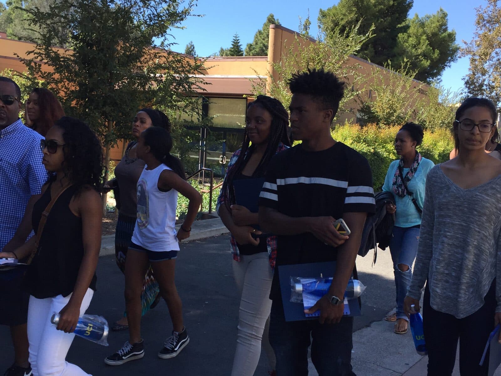 Scholars walking together along a campus path on a sunny day